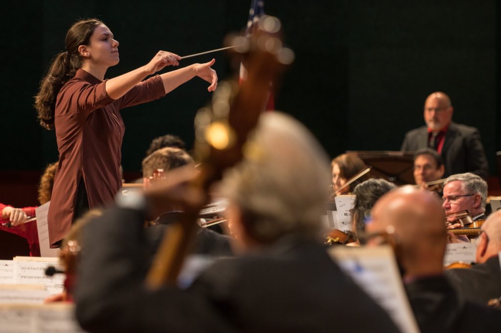 Corpus Christi Symphony Orchestra Conductor shown conducting through the crowd of musicians on stage.