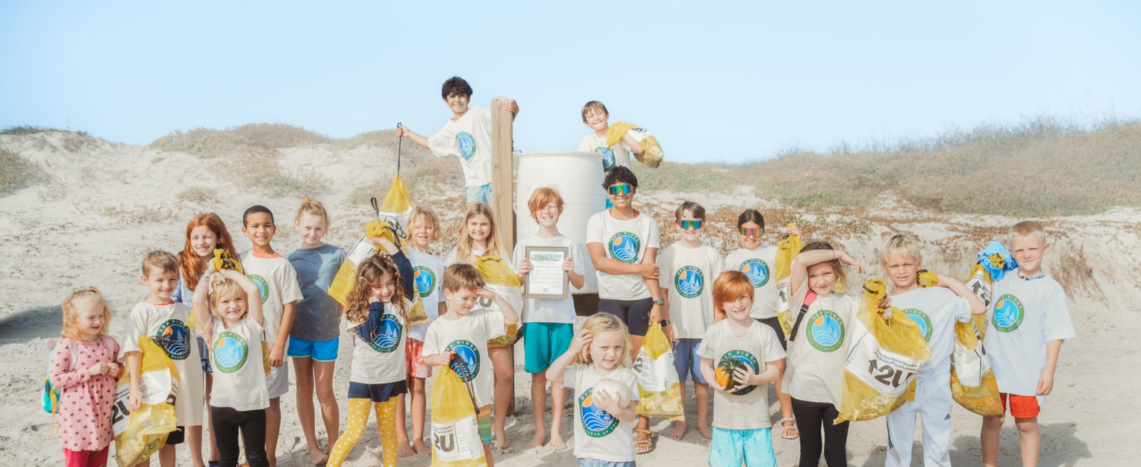 The Sea Pines Beach Clean Up Crew, made up of more than a dozen kids, stands proudly on Sea Pines Beach, where they work to keep the coast clean.