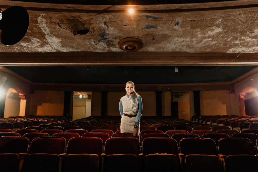 CCPATCH Executive Director, Cheryl Votzmeyer-Rios, stands center in the auditorium of The Ritz Theatre.