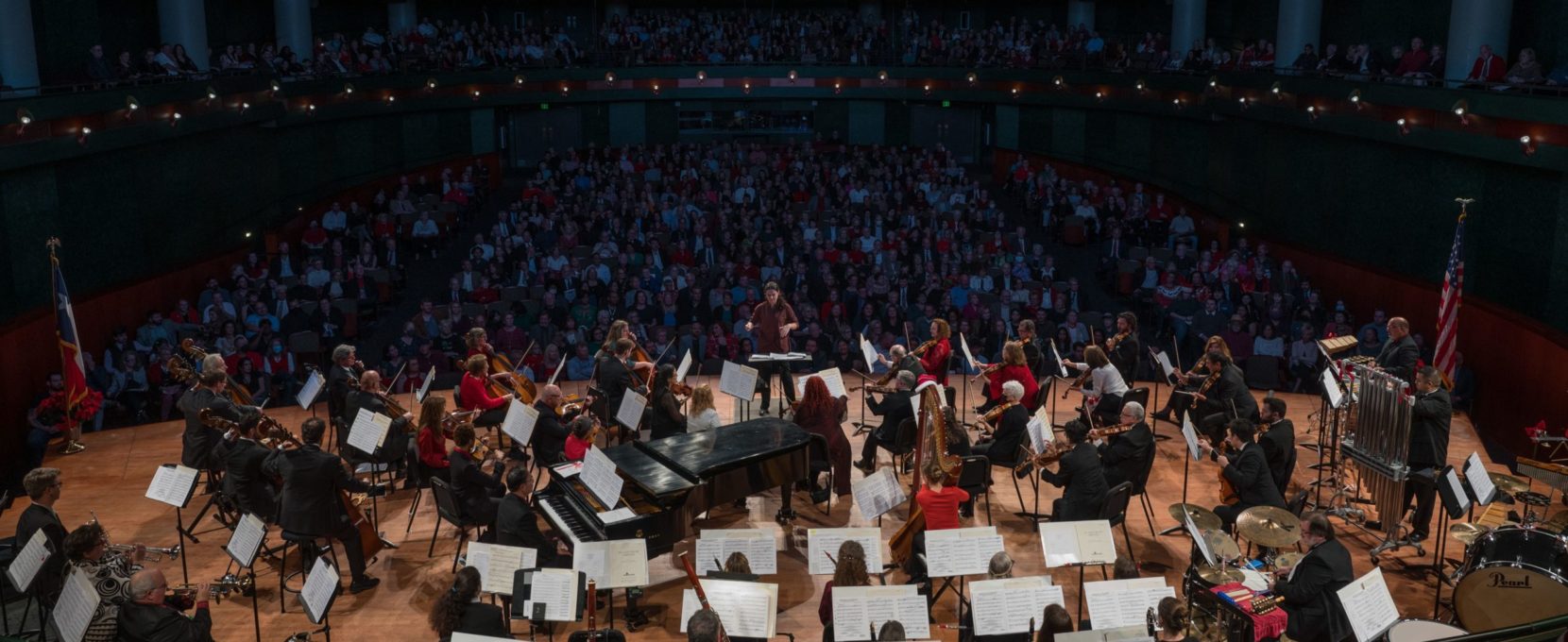 The Corpus Christi Symphony Orchestra sits center-stage in the Performing Arts Center as the full crowd enjoys an orchestral performance.