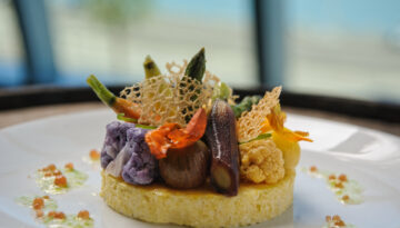 Venue by the Bay serving Smoked Corn Cake & Poached Heirloom Vegetables, corn “milk”, chive oil, tomato caviar, and roast garlic tuille at the American Bank Center.