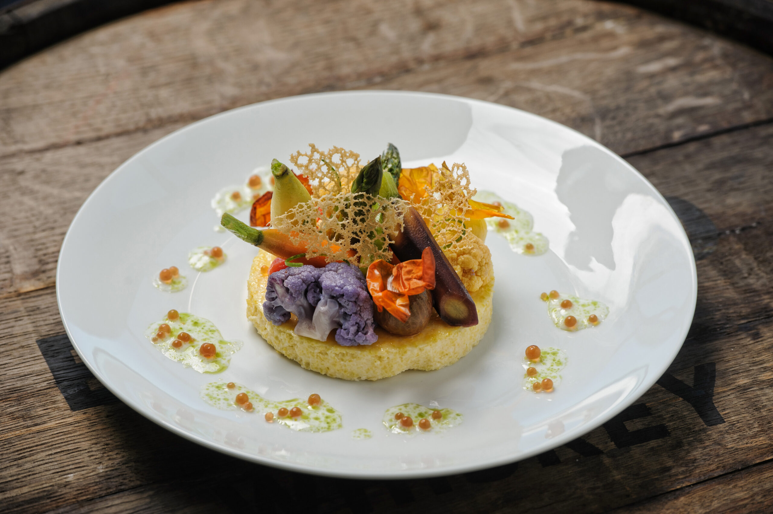 Venue by the Bay serving Smoked Corn Cake & Poached Heirloom Vegetables,corn “milk”, chive oil, tomato caviar, and roast garlic tuille at the American Bank Center.