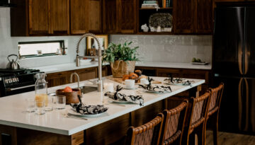 A gorgeous wooden-cabinet lined kitchen, topped with white stone countertops and beautifully styled. Here are tips on styling your kitchen island.