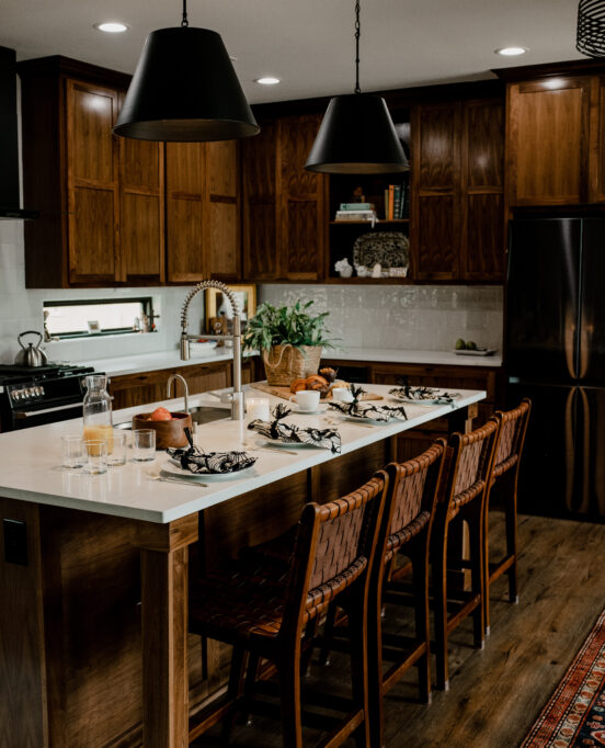 A gorgeous wooden-cabinet lined kitchen, topped with white stone countertops and beautifully styled. Here are tips on styling your kitchen island.