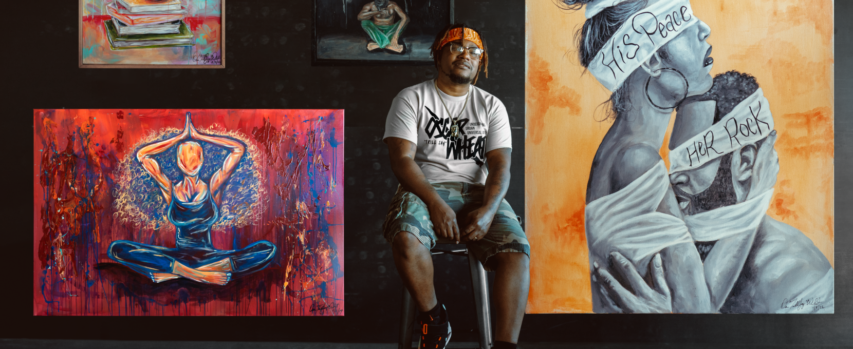 Corpus Christi artist Oscar "TrillJay" Wheat sits on a stool in front of a wall adorned with several of his paintings.