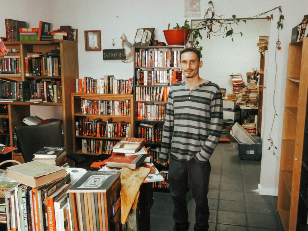 Owner Carter Little standing among the shelves in Black Cat Books