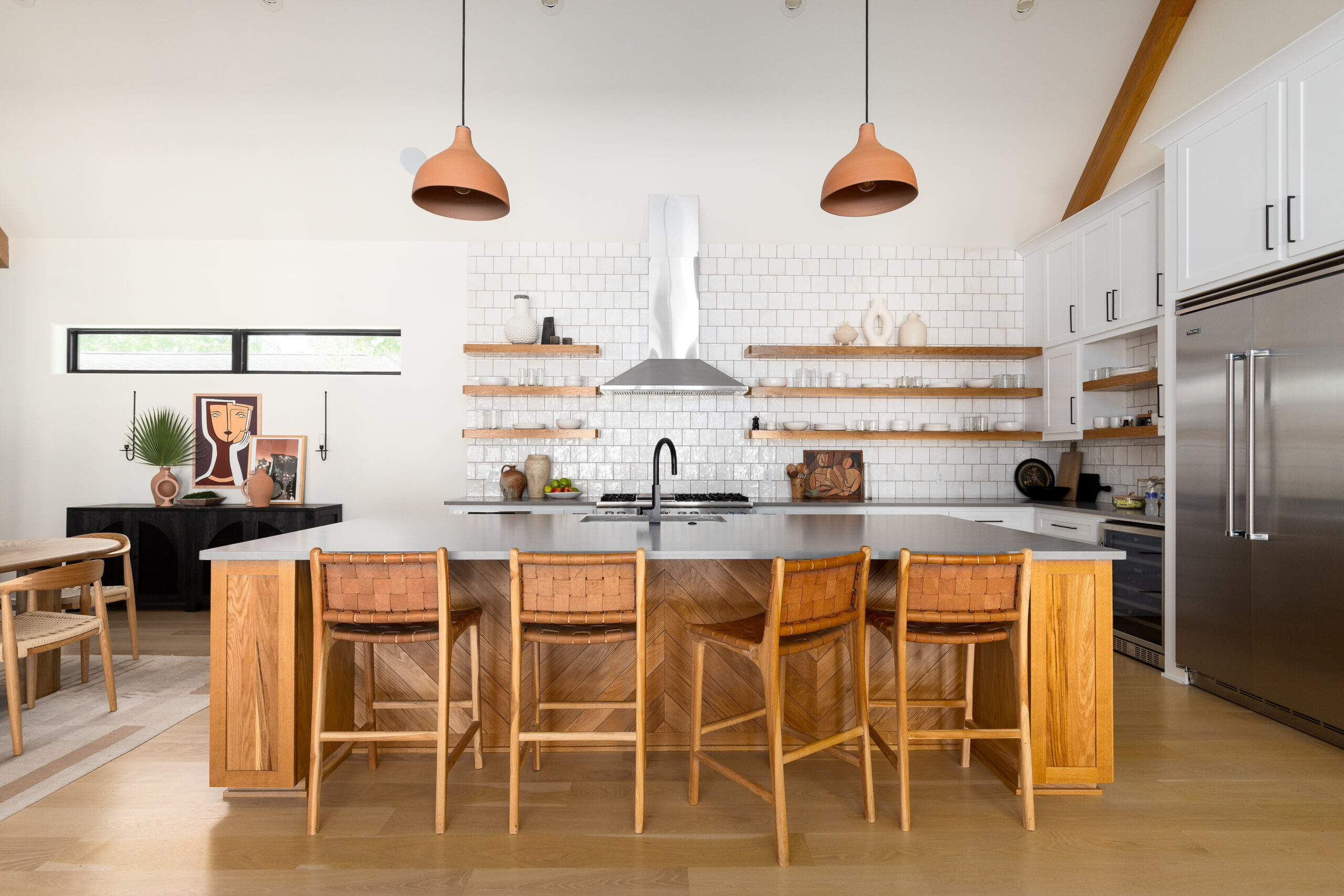 The kitchen of this Hyde Park home in Corpus Christi features a colossal wood island with chevron detailing and a counter-to-ceiling backsplash that draws the eye upward to the vaulted ceilings.