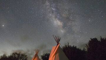 A photograph on view in the Art Museum of South Texas exhibition shows tents of The Lakota People during a Sun Dance Ceremony taken at night.