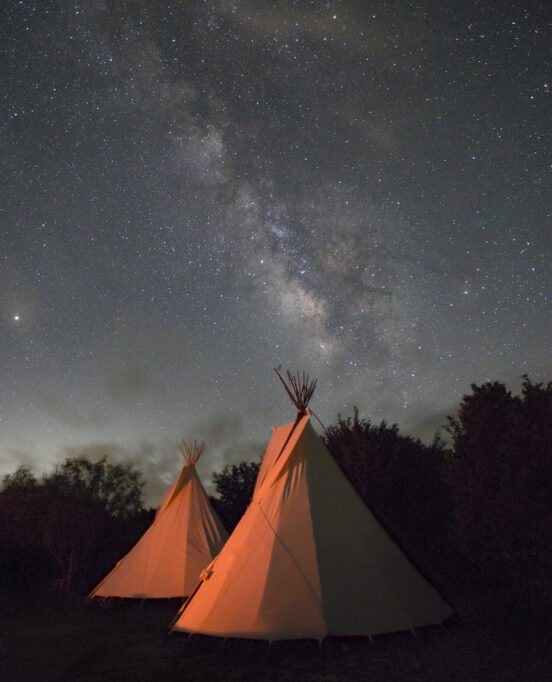 A photograph on view in the Art Museum of South Texas exhibition shows tents of The Lakota People during a Sun Dance Ceremony taken at night.