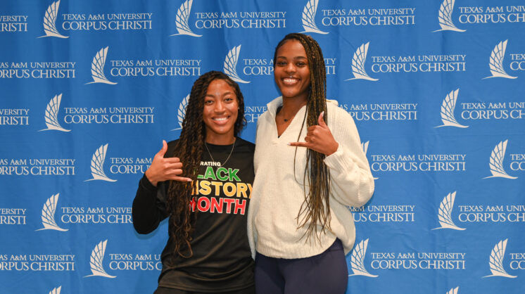 Two TAMU-CC students pose for a photo in front of a blue backdrop.