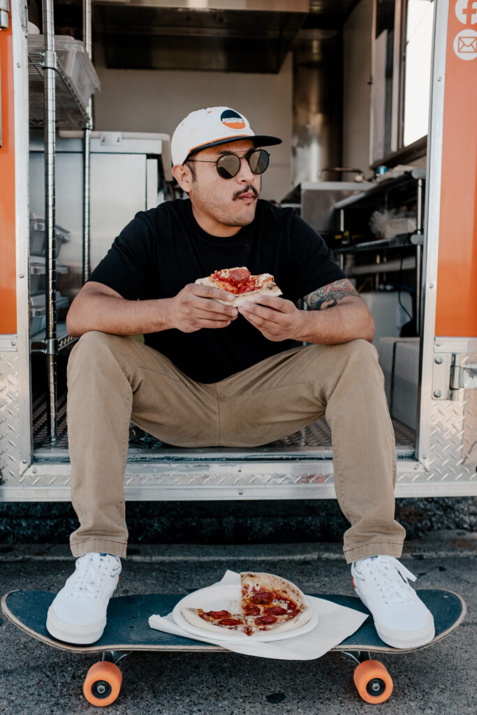 Marty McPies owner Martin Flores eats a slice of pizza outside his food truck.