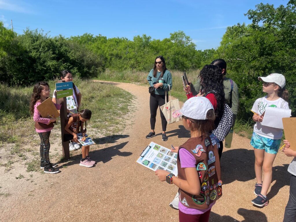 A crowd of kids listen attentively as an Oso Bay Wetlands staff member guides them through a trail in Corpus Christi, Texas.
