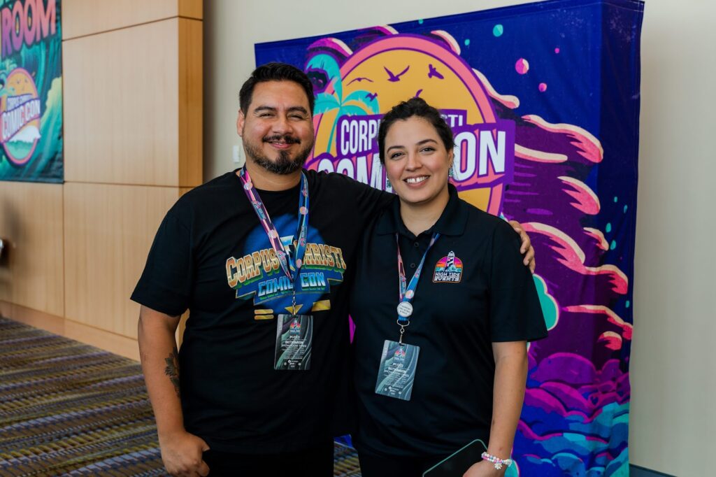 Daniel and Meagan Benavides, two of the founding owners of Corpus Christi Comic Con, pose for a photo in front of the event's logo. 
