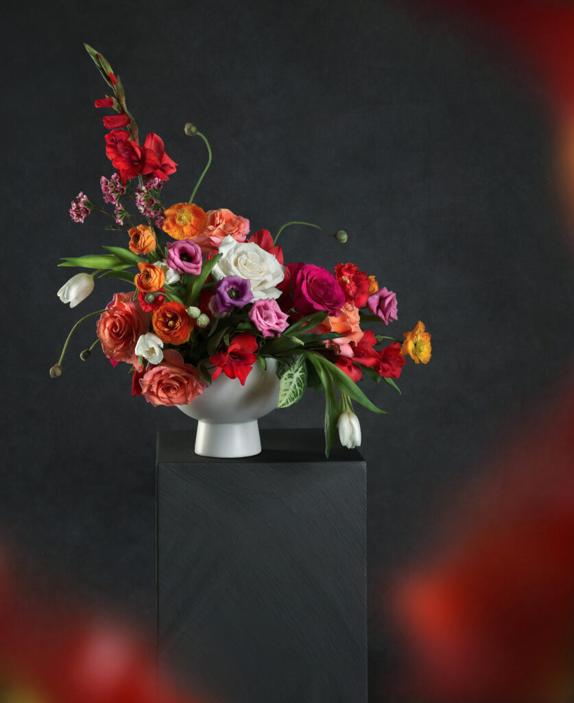 An artful floral piece created by Wild Veggie Bouquet in Corpus christi sits on a pedestal. 