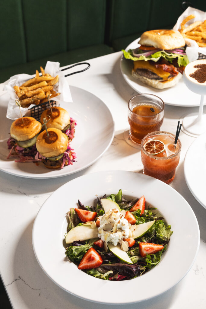 A full table of plated food and drinks at Stouts at the Shore in Port Aransas, Texas. 