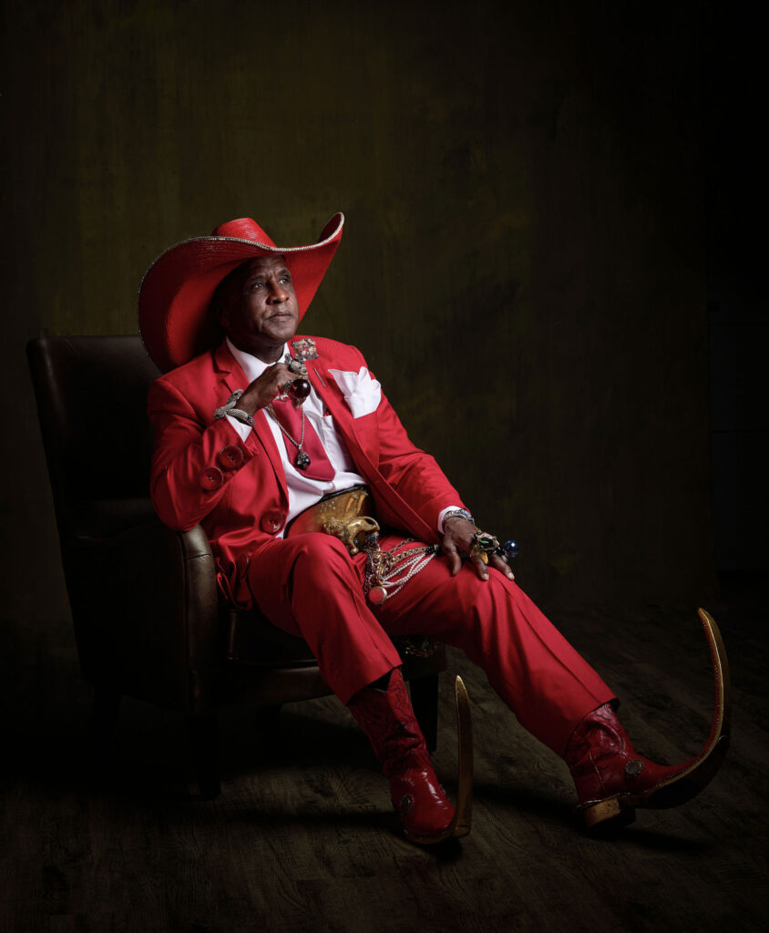 Ronnie “Pointy Boots” Mathis poses for a portrait in a red suit. 
