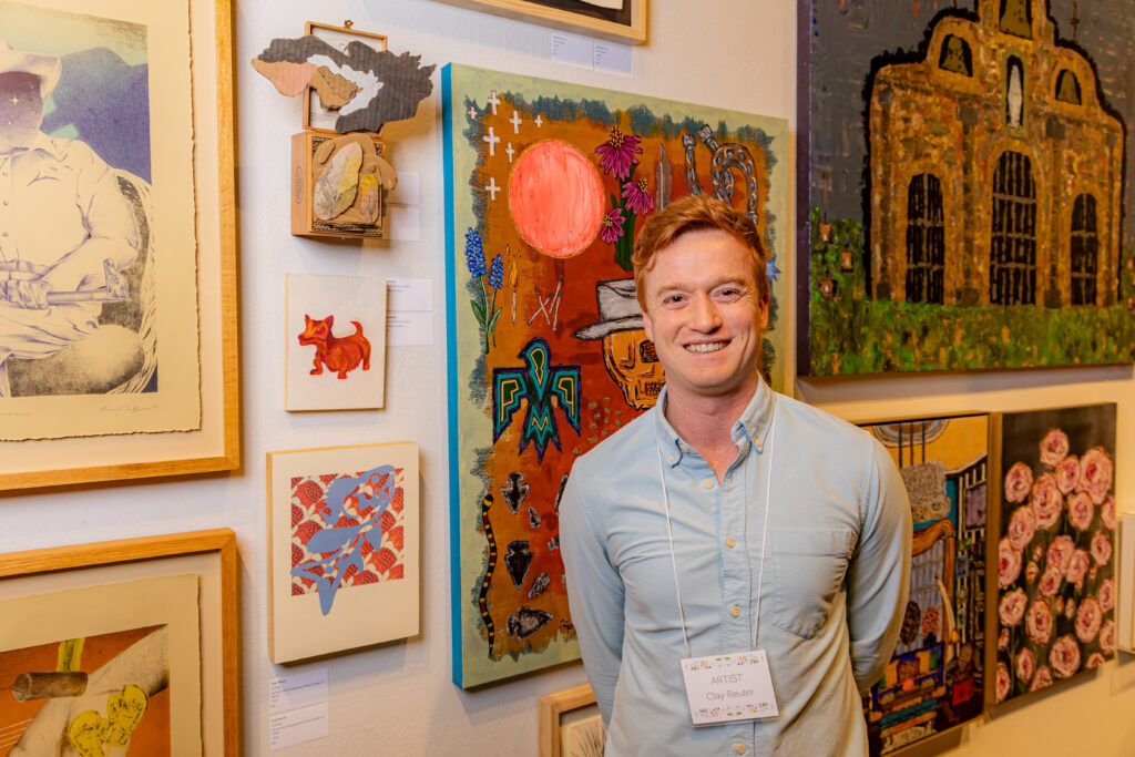 Clay Reuter stands in front of art in the Weil Gallery at Texas A&M University-Corpus Christi for its annual La Merienda event. 