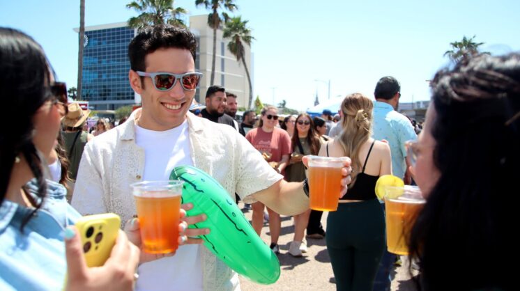 A man and friends conversing while holding beers at Picklefest in Corpus Christi.