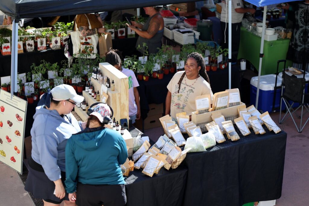 Two individuals looking at a vendor table at GROW Local South Texas Farmers Market in Corpus Christi, Texas.