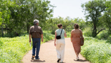 Three adults walk down a paved trail.