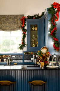 A plush Santa figurine sits on the dark counter surrounded by blue cabinets and other holiday decorations in Stuart and Shannon White's home.