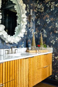 Stuart and Shannon White's Christmas-themed sink featuring holiday china, a large white-rimmed mirror and wooden paneling on the cabinets.