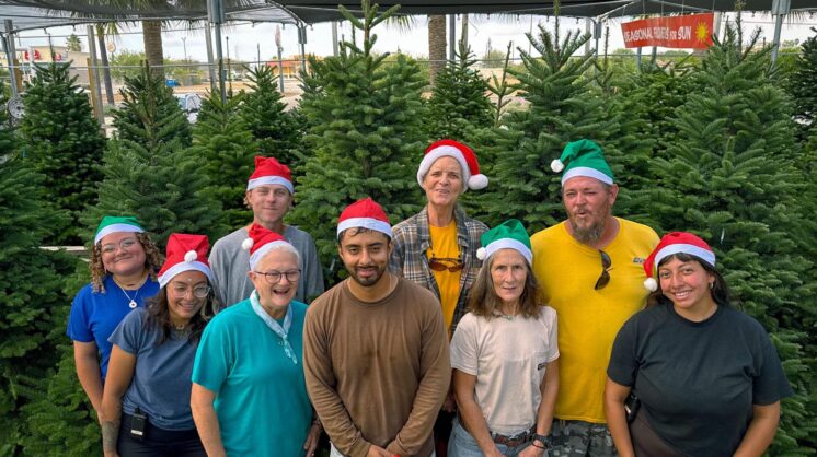 The crew at Gill's Landscaping pose for a photo in front of their Christmas trees.