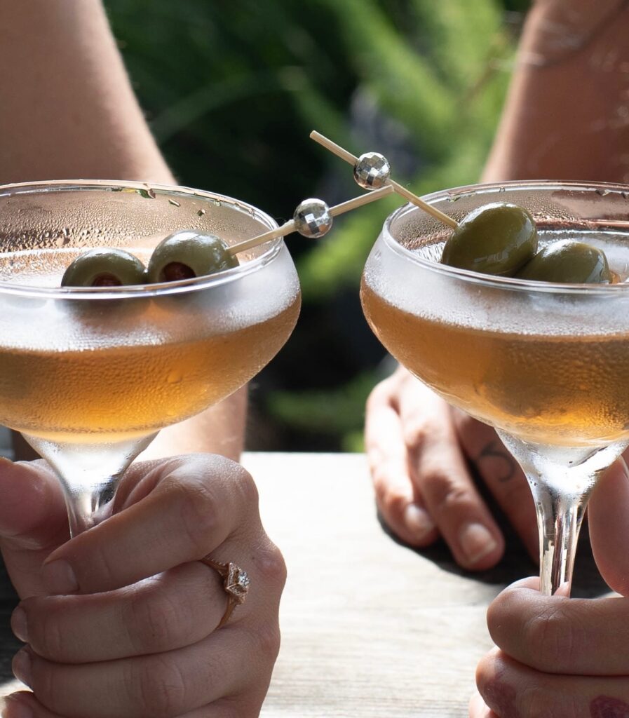 Two martinis being held by girls. 