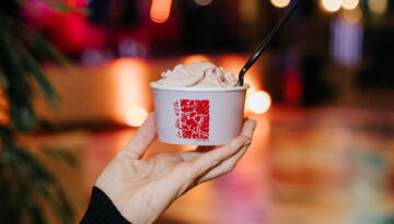 A hand holds up a cup of gelato at a Fauvist Fête debutante party.