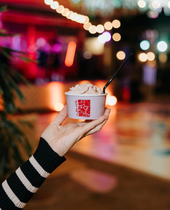 A hand holds up a cup of gelato at a Fauvist Fête debutante party.