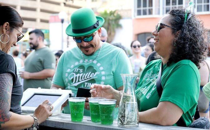 Two people buying green beer at the St. Paddy's Festival in downtown Corpus Christi.