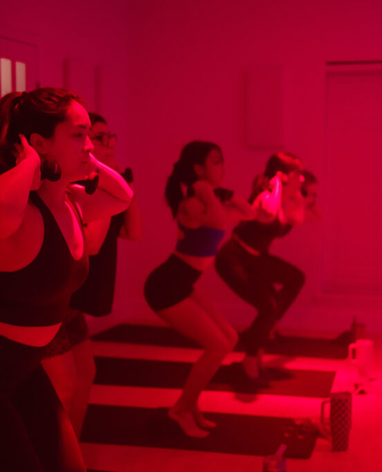 A group of three girls doing squats at LUMA Fitness Studio.