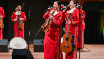 Two women on stage at the Performing Arts Center in Corpus Christi, Texas singing at the annual ¡Festival de Mariachi! en la Isla.