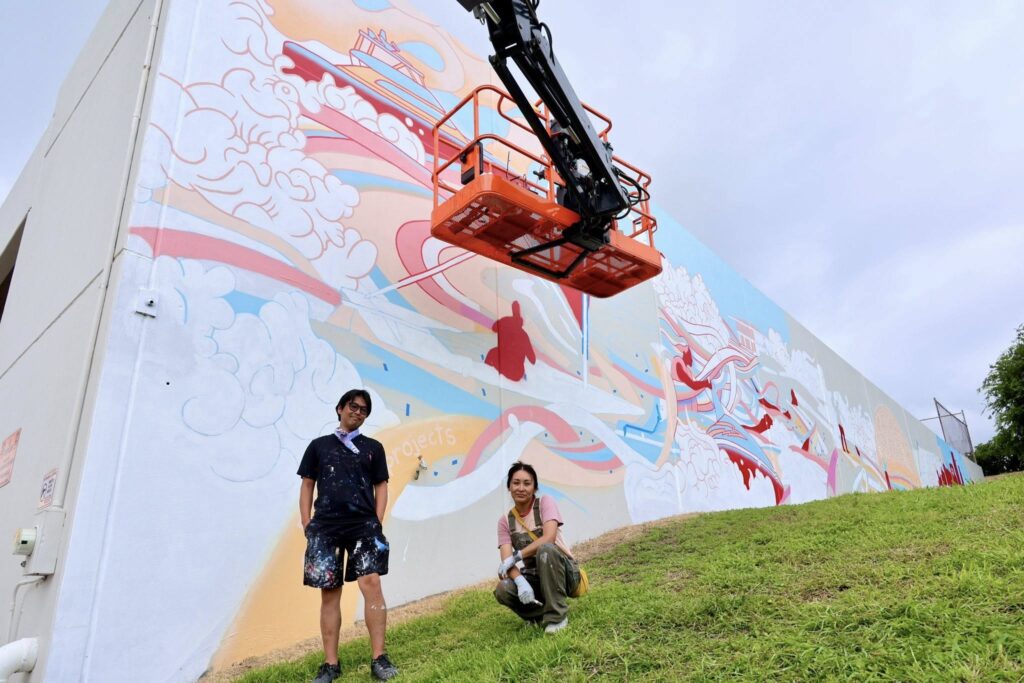 Los Angelos artists, DB Studios, stands in front of their mural in progress during Mural Fest 2026 in Corpus Christi. 
