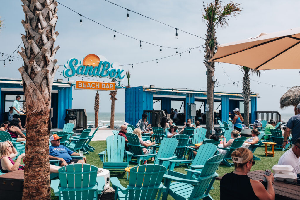 Large group of people gathering in chairs at the Sandbox Beach Bar in Corpus Christi, Texas. 
