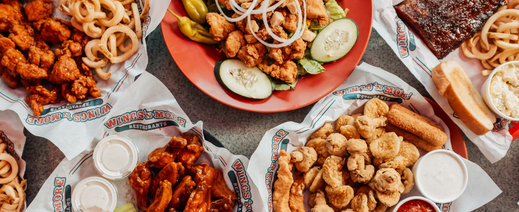 Overhead shot of wings, french fries, onion rings, and a sald from Wings N More in Corpus Christi.