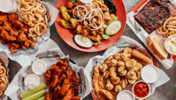 Overhead shot of wings, french fries, onion rings, and a sald from Wings N More in Corpus Christi.