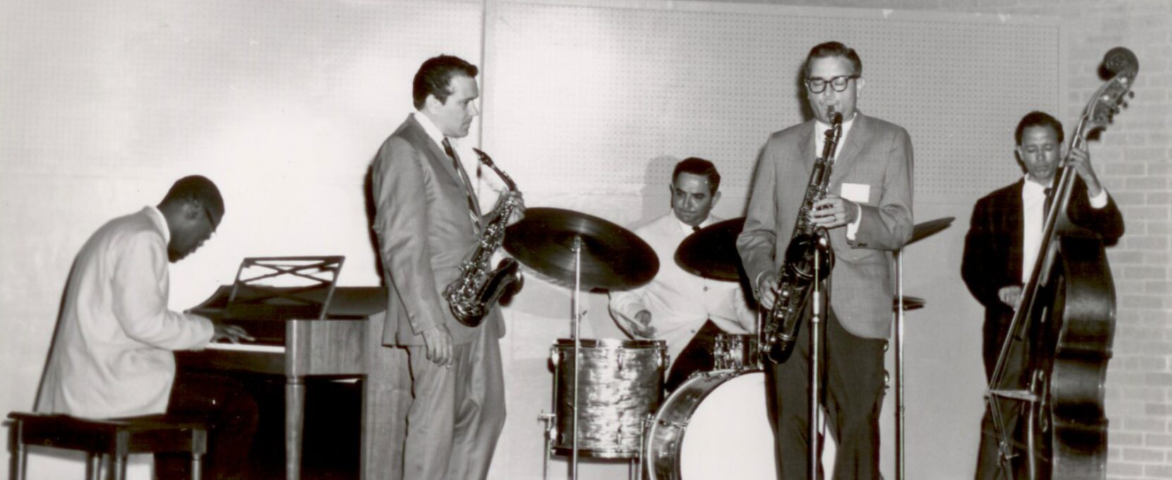 A group of jazz musicians perform onstage at the Texas Jazz Festival. The photo is in black and white.
