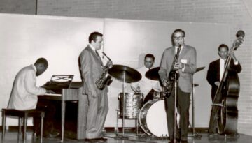 A group of jazz musicians perform onstage at the Texas Jazz Festival. The photo is in black and white.