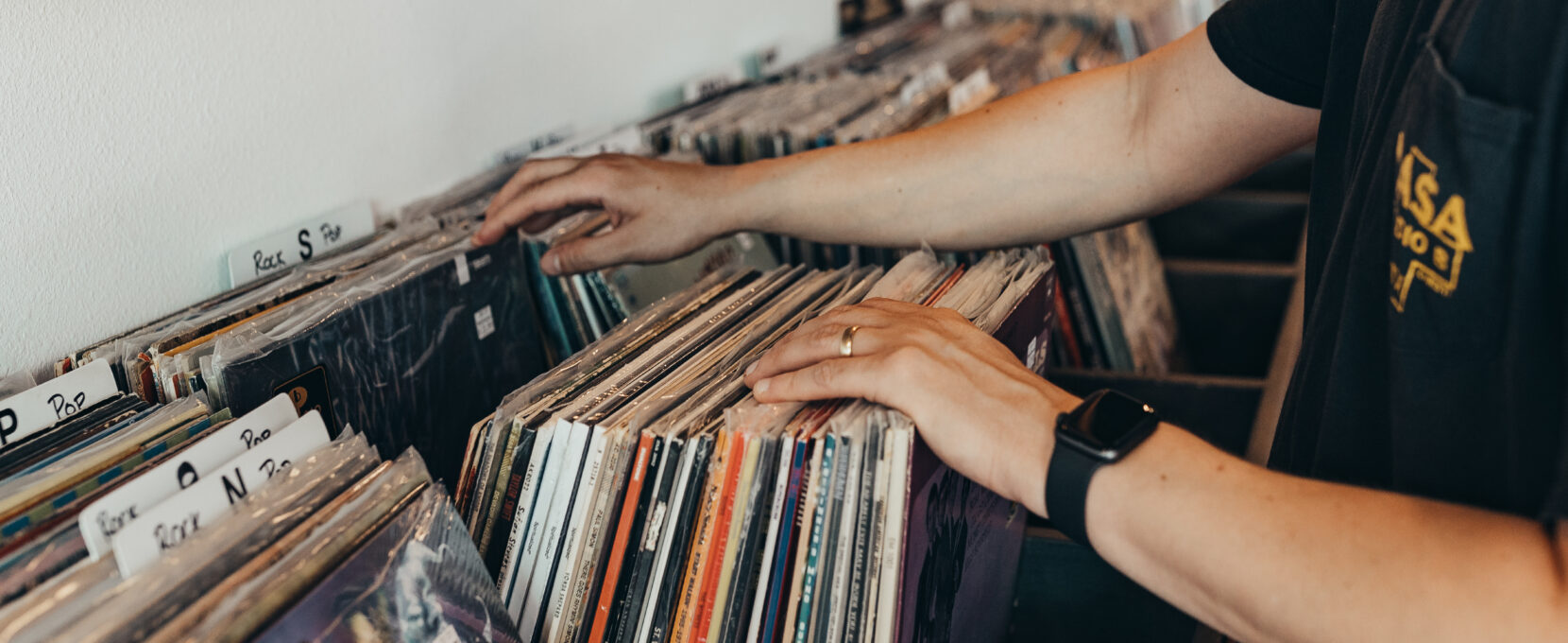 An individual flips through vinyl records on a shelf at Hybrid Records in Corpus Christi, Texas.