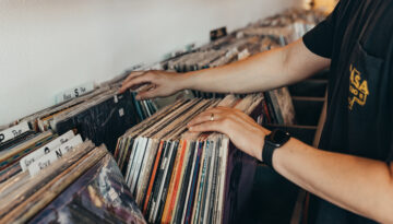 An individual flips through vinyl records on a shelf at Hybrid Records in Corpus Christi, Texas.